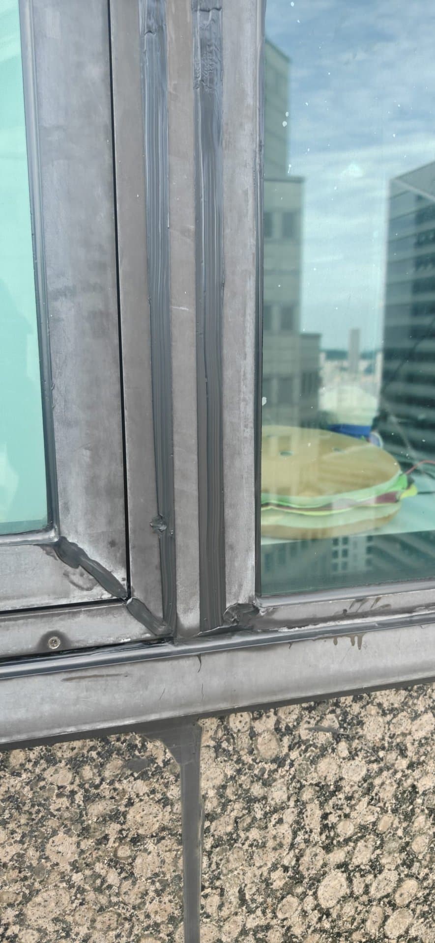 Close-up of a freshly applied Hydroseal silicone sealant joint on a window frame during façade waterproofing on a suburban retail mall in Singapore