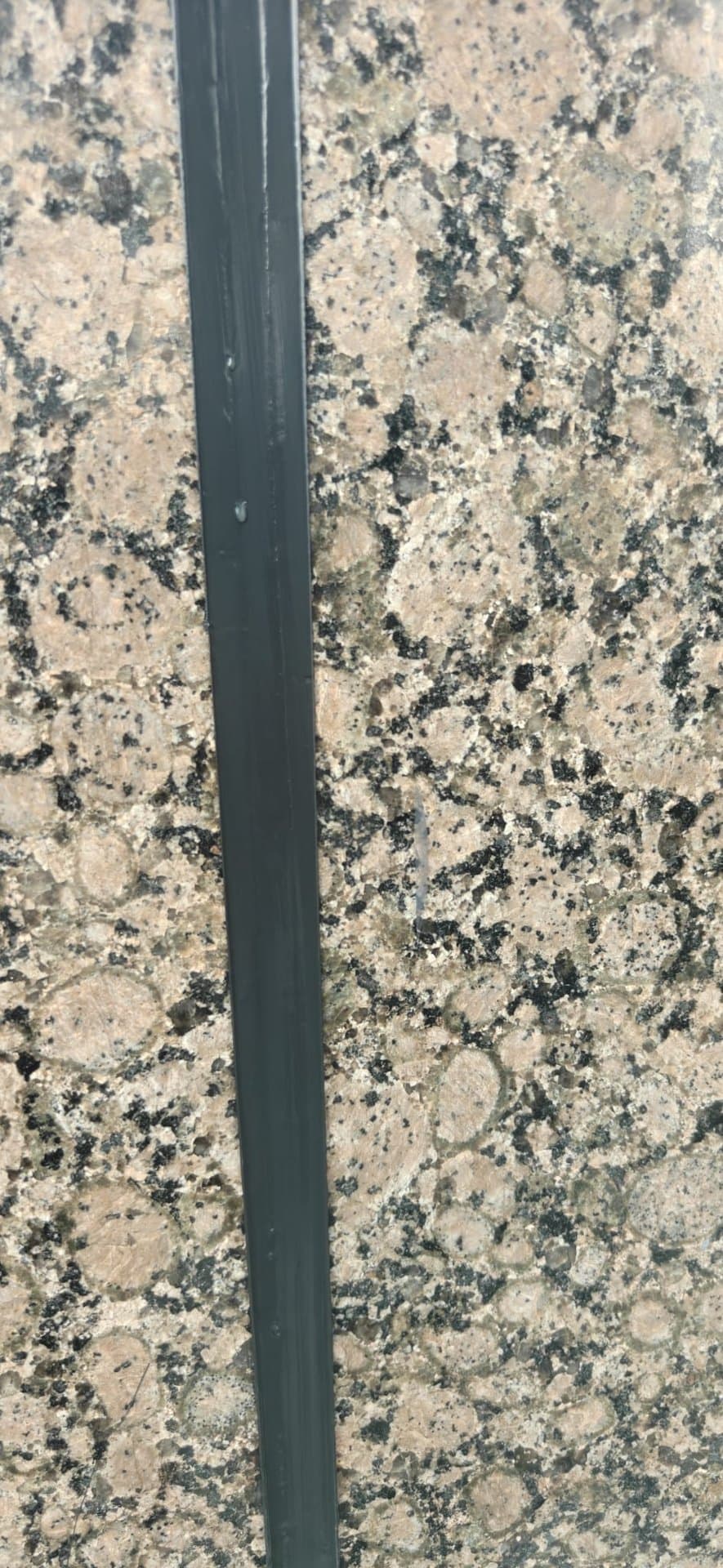 Finished clean grey polyurethane sealant bead running along a window-head joint on a granite façade after Hydroseal rope-access works in Singapore