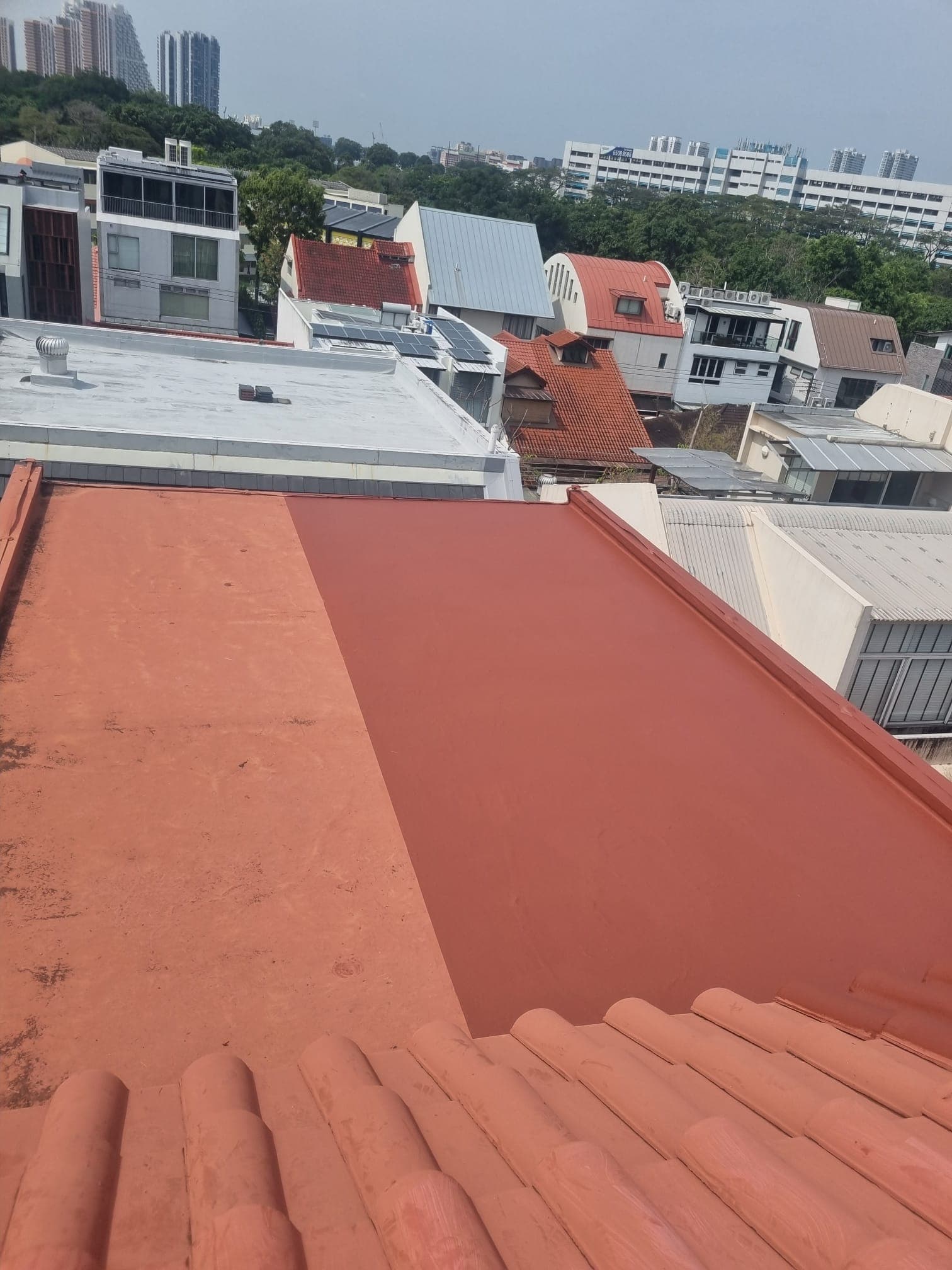 Completed waterproof coating on a tiled landed-home roof with the Singapore skyline behind