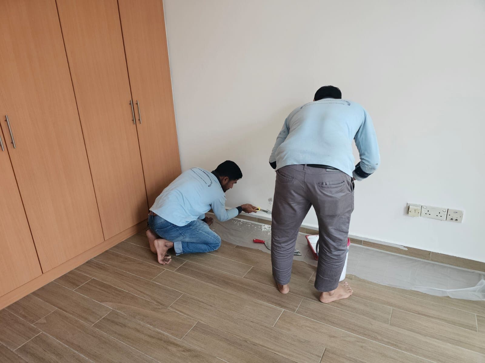 Hydroseal technician repairing a water-damaged interior wall base in a Singapore condominium
