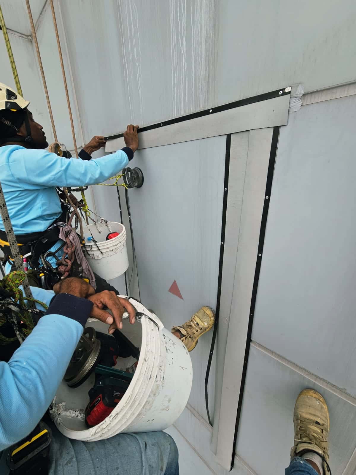 Rope-access technician sealing an external wall joint in Singapore
